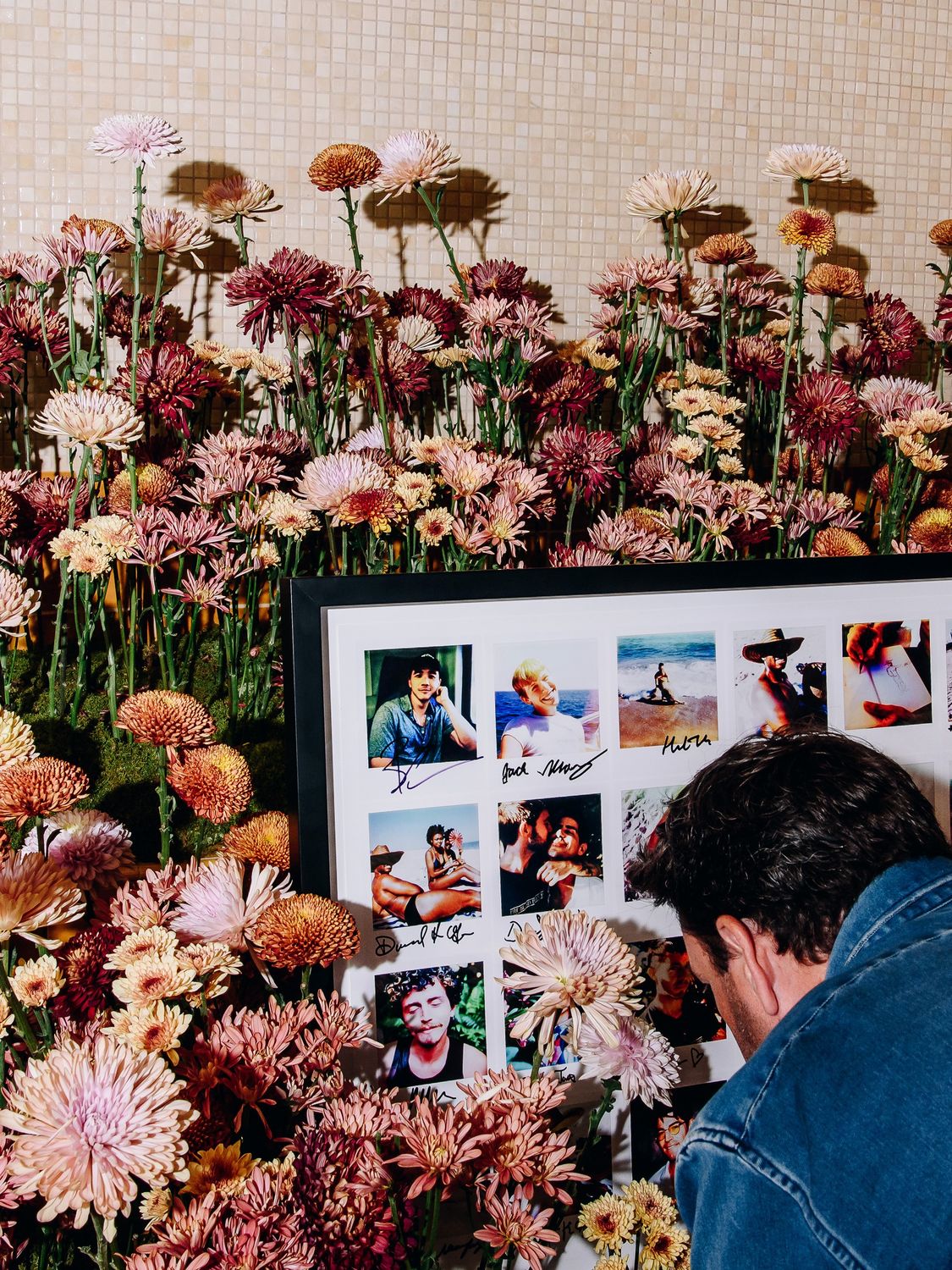 Chrysanthemum flower wall in dusty pink and amber beside a framed photo art display, members club, New York