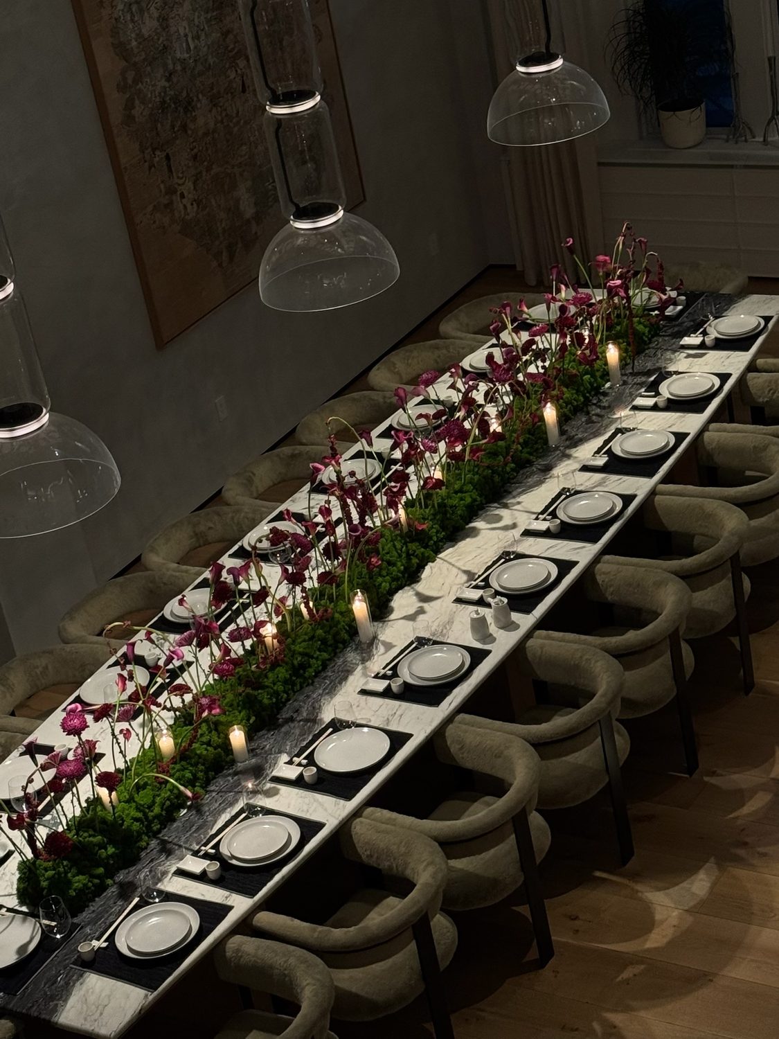 Long marble dining table with a moss-and-calla-lily runner and candles, downtown New York