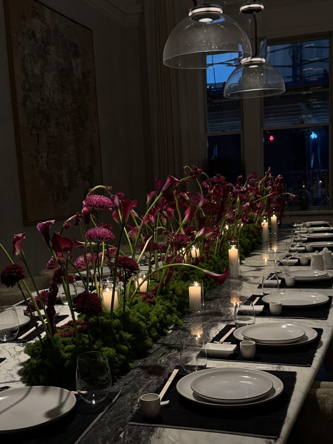 Long marble dining table with a moss-and-calla-lily runner and candles, downtown New York, by Kuration Studio
